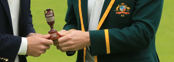 Cricket players from Australia and England hold the Ahes trophy in their hands